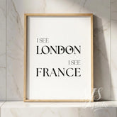 Minimal typography bathroom poster with the text “I See London I See France,” framed in natural wood and placed against a marble wall.