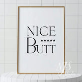 Minimal bathroom wall art featuring the text “Nice Butt” with five stars, displayed in a light wood frame against tiled walls.