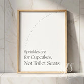 Bathroom quote wall art in a natural wood frame leaning on a marble shelf, adding subtle humor to a clean bathroom setting.