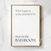 Minimal bathroom wall art featuring the quote “What happens in the bathroom, stays in the bathroom,” displayed in a slim gold frame on a marble wall.