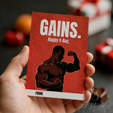 Hand holding red gym-themed Valentine card with muscular figure, NJS studio branding visible.