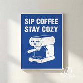 Framed poster with 'Sip Coffee Stay Cozy' text and an espresso machine illustration on a blue background.