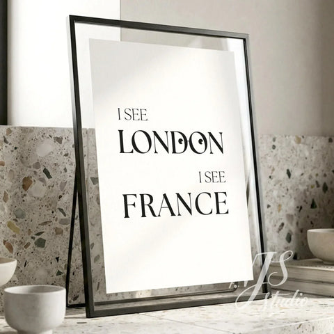 Funny bathroom wall art featuring the phrase “I See London I See France,” displayed in a slim black frame on a modern stone bathroom counter.