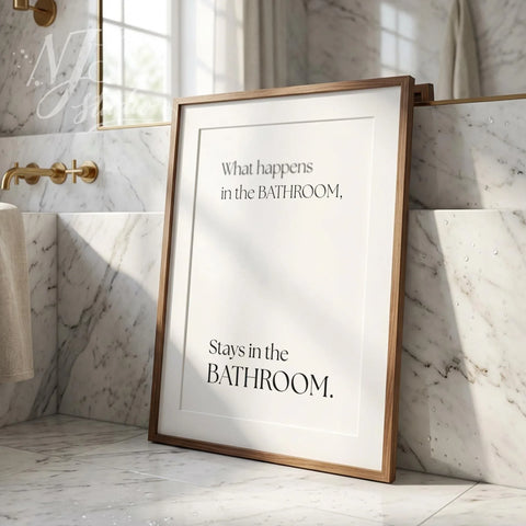 Humorous bathroom wall art print leaning against a tiled wall, featuring the quote “What happens in the bathroom, stays in the bathroom.”