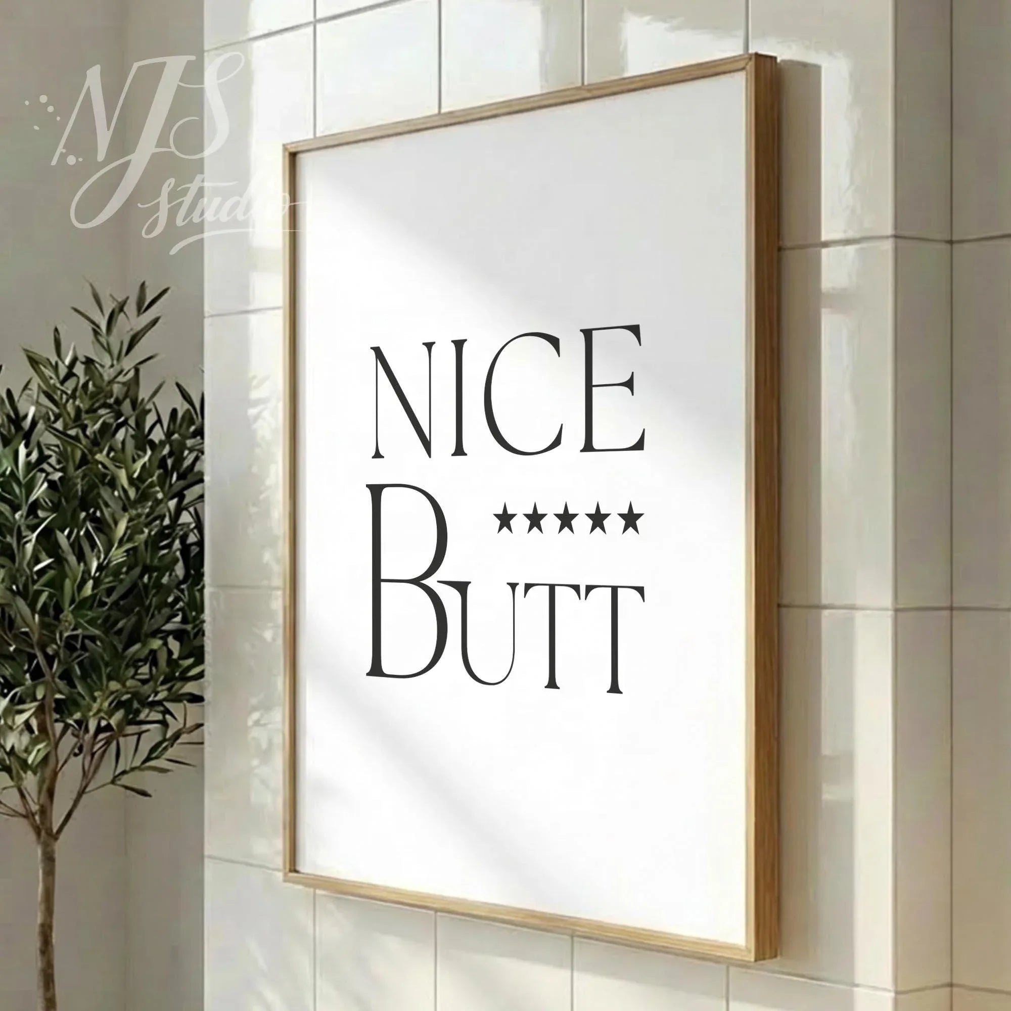 Modern bathroom quote print featuring “Nice Butt” and star rating, styled in a vertical wood frame on tiled flooring.