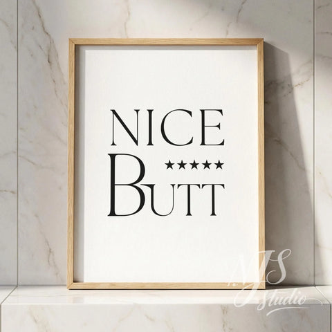 Typography bathroom poster with the phrase “Nice Butt” and five stars, framed in wood and placed against a marble tile wall.