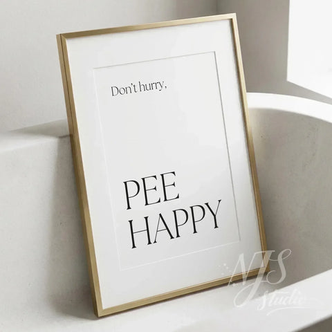 Minimal bathroom wall art featuring the quote “Don’t hurry, Pee Happy,” displayed in a slim gold frame beside a modern bathtub.