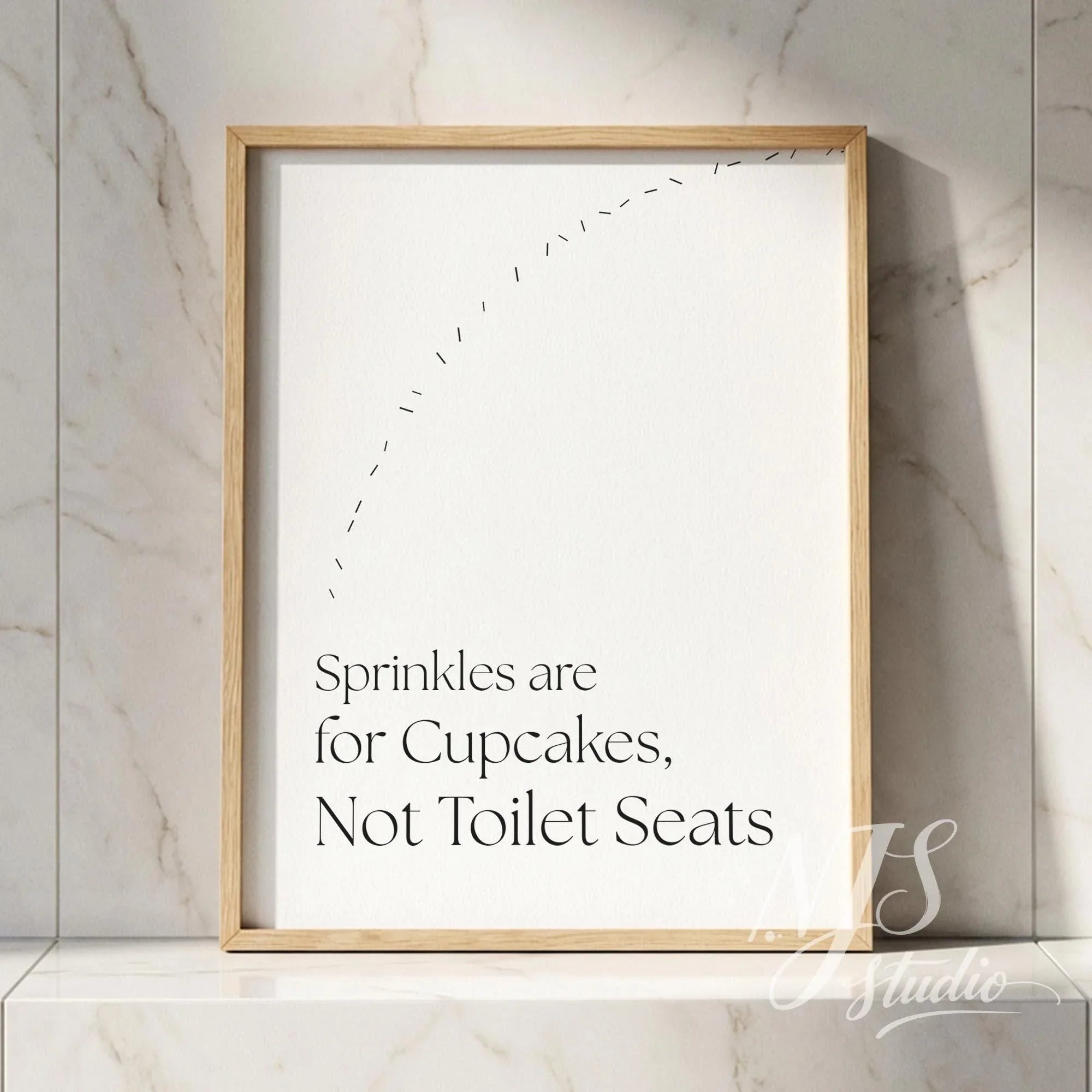 Bathroom quote wall art in a natural wood frame leaning on a marble shelf, adding subtle humor to a clean bathroom setting.