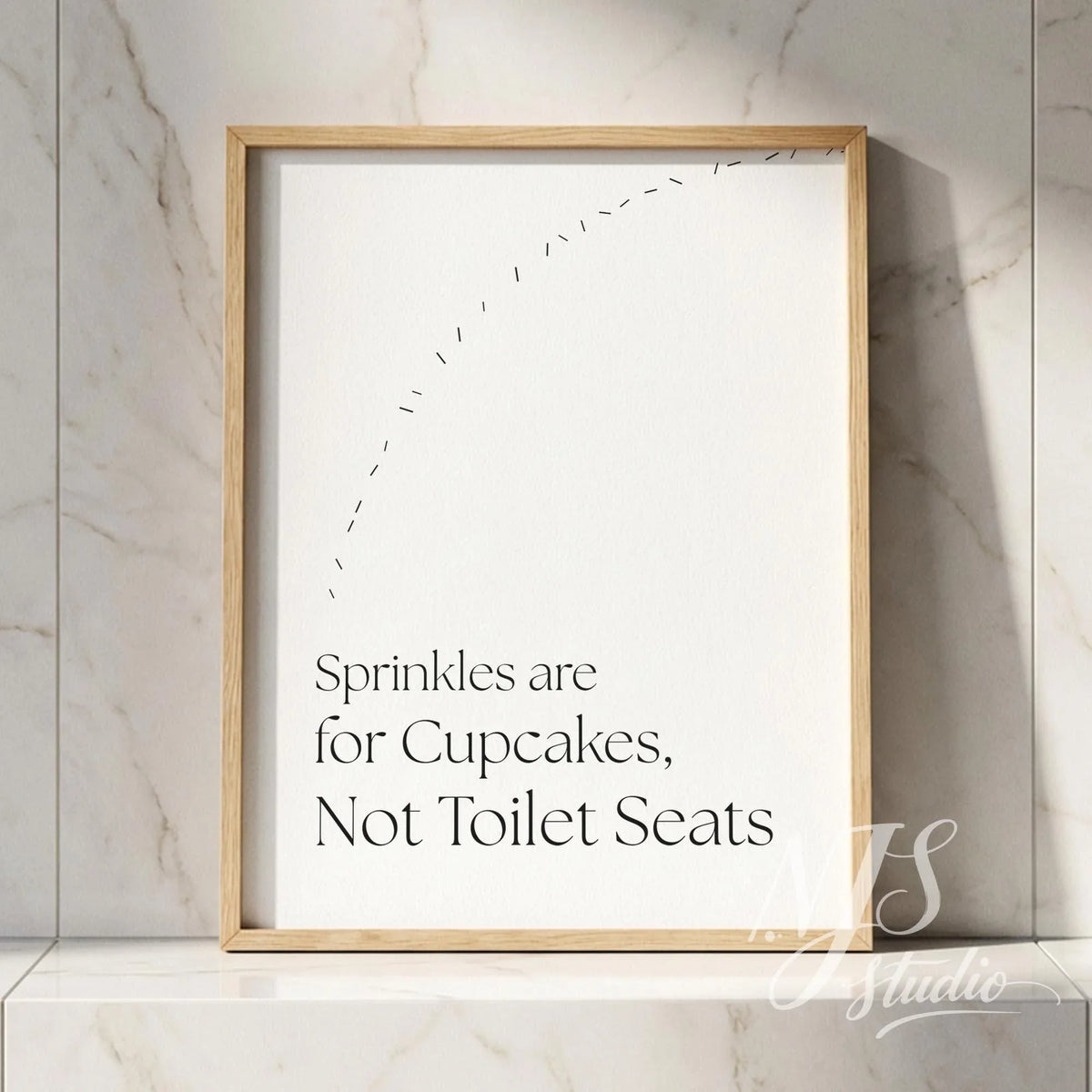 Bathroom quote wall art in a natural wood frame leaning on a marble shelf, adding subtle humor to a clean bathroom setting.