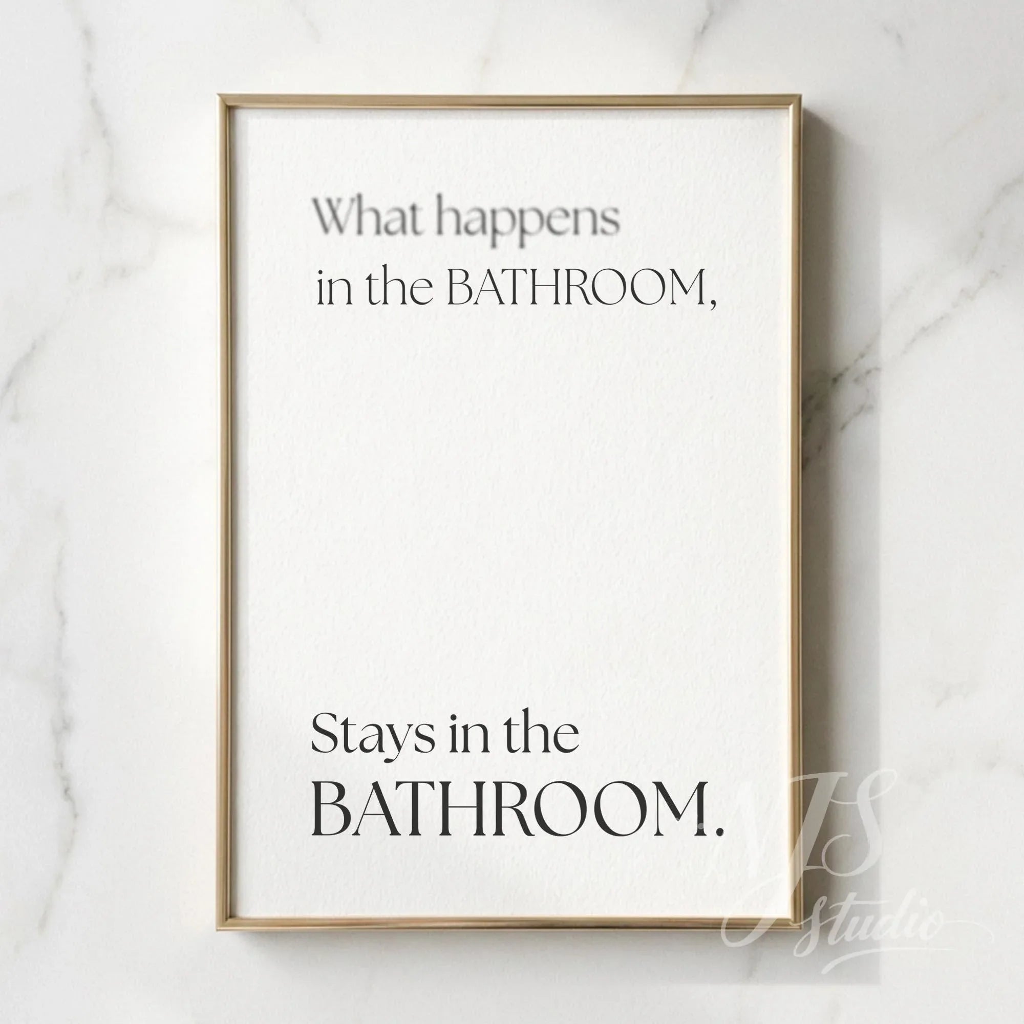 Minimal bathroom wall art featuring the quote “What happens in the bathroom, stays in the bathroom,” displayed in a slim gold frame on a marble wall.