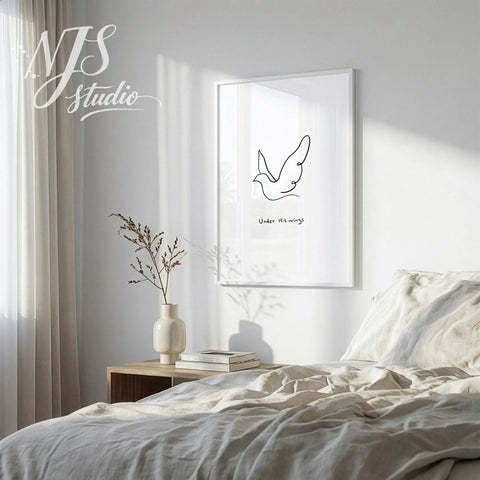 Peaceful bedroom setting with sunlight hitting a framed Under His Wings scripture print on a bedside table.