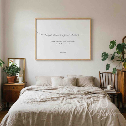 Large horizontal framed print reading Keep love in your heart hanging above a bed with beige linen bedding.