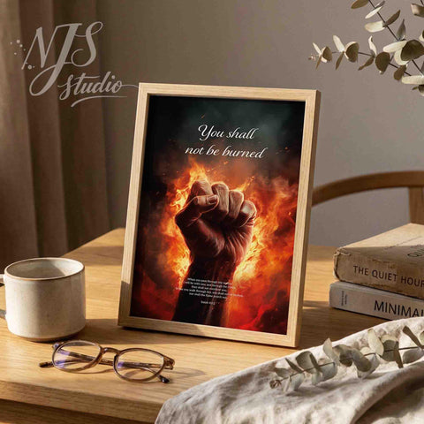 Framed bible verse print on a desk with the quote You shall not be burned.