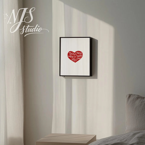 Black framed playful Christmas typography poster hanging on a wall next to a bed.
