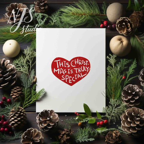 Christmas flatlay with pinecones and greenery surrounding a cute red heart holiday art print.