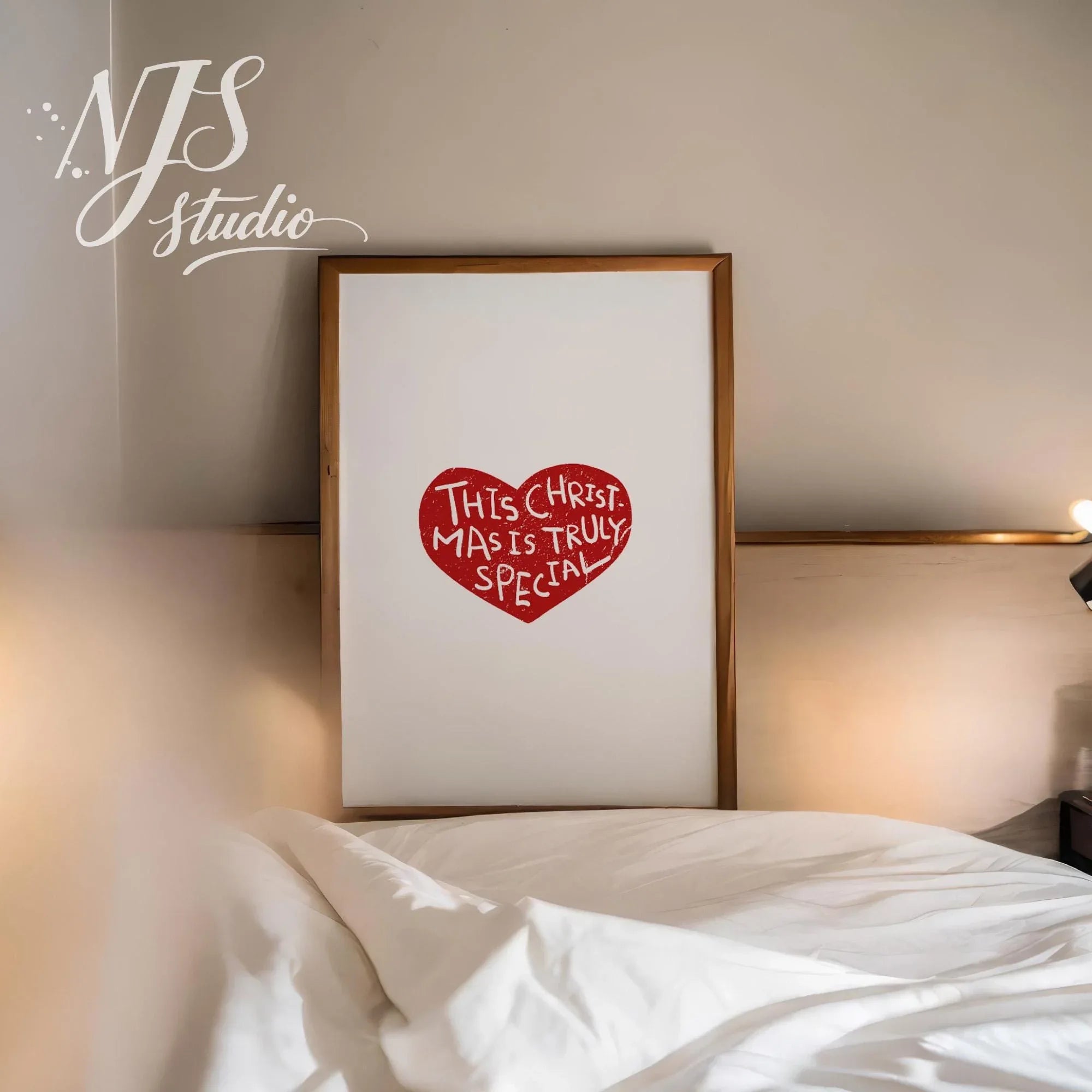Large framed Christmas heart art print leaning against a wall in a cozy bedroom setting.