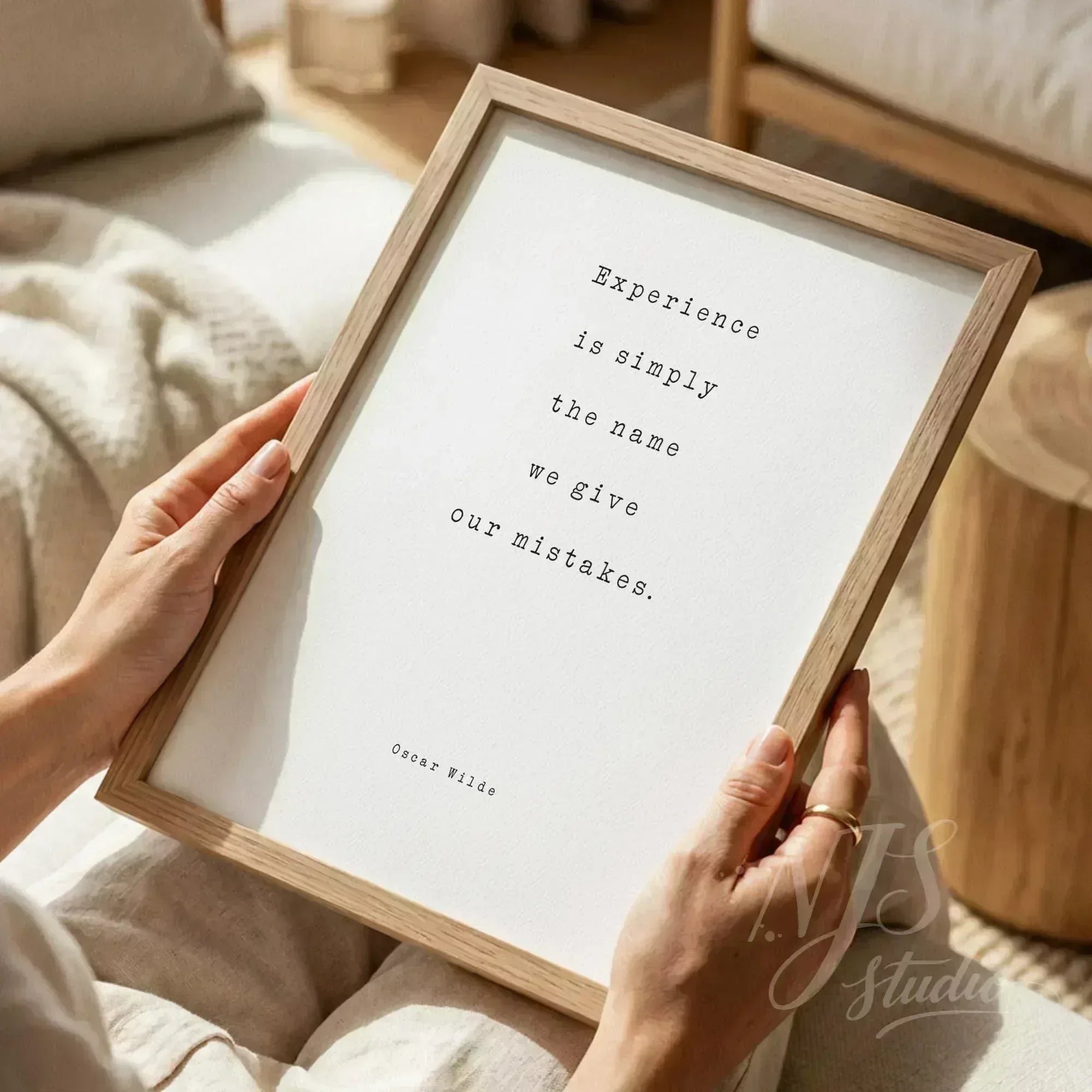 Close up of person holding a framed quote print while sitting comfortably, cozy reading nook vibe.