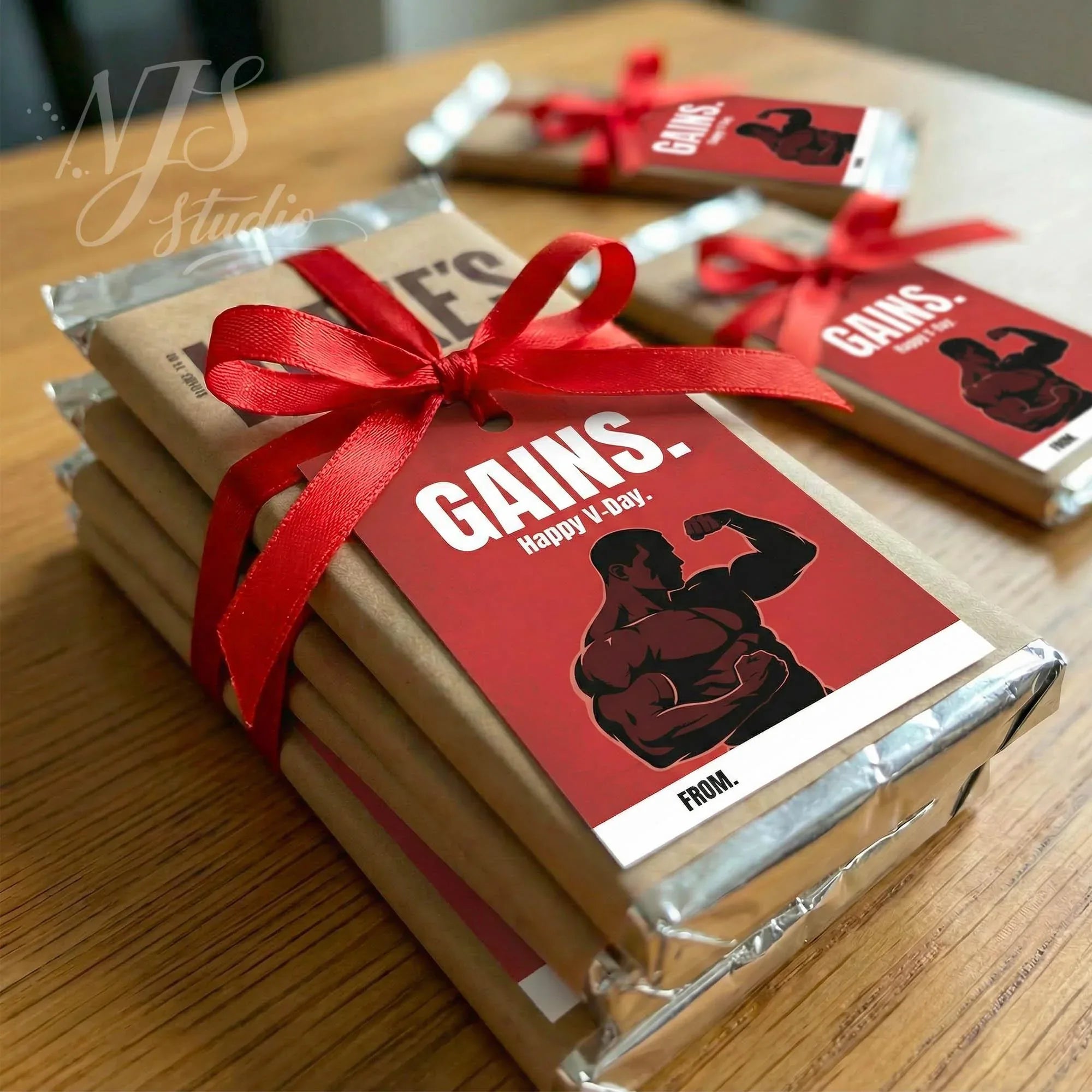 Fitness-themed chocolate bars with gift tags, red bows, and muscle graphic by NJS studio.
