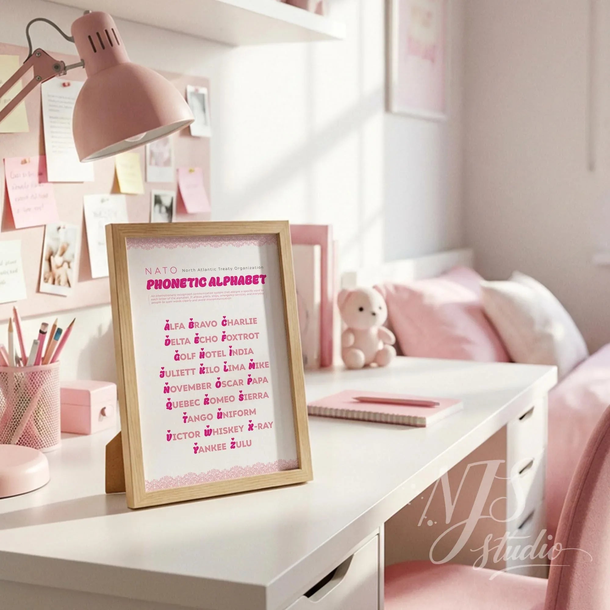 Wood framed girly wall art standing on a white desk with pink office supplies, pencil holder, and lamp.