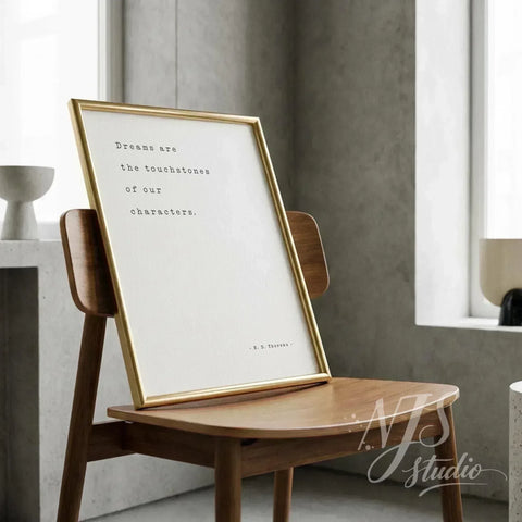 Minimalist gold framed poster leaning on a wooden chair in a modern interior.