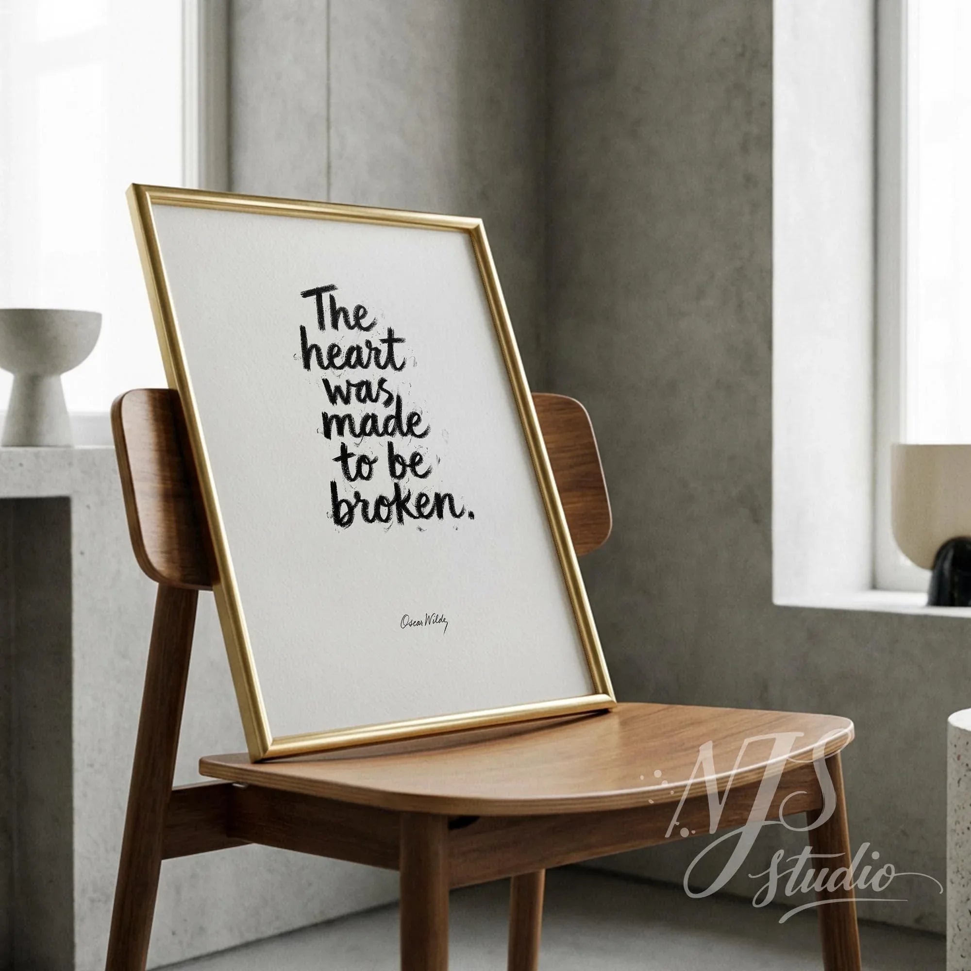 Minimalist gold frame leaning on a wooden chair, displaying an inspirational quote about the heart.