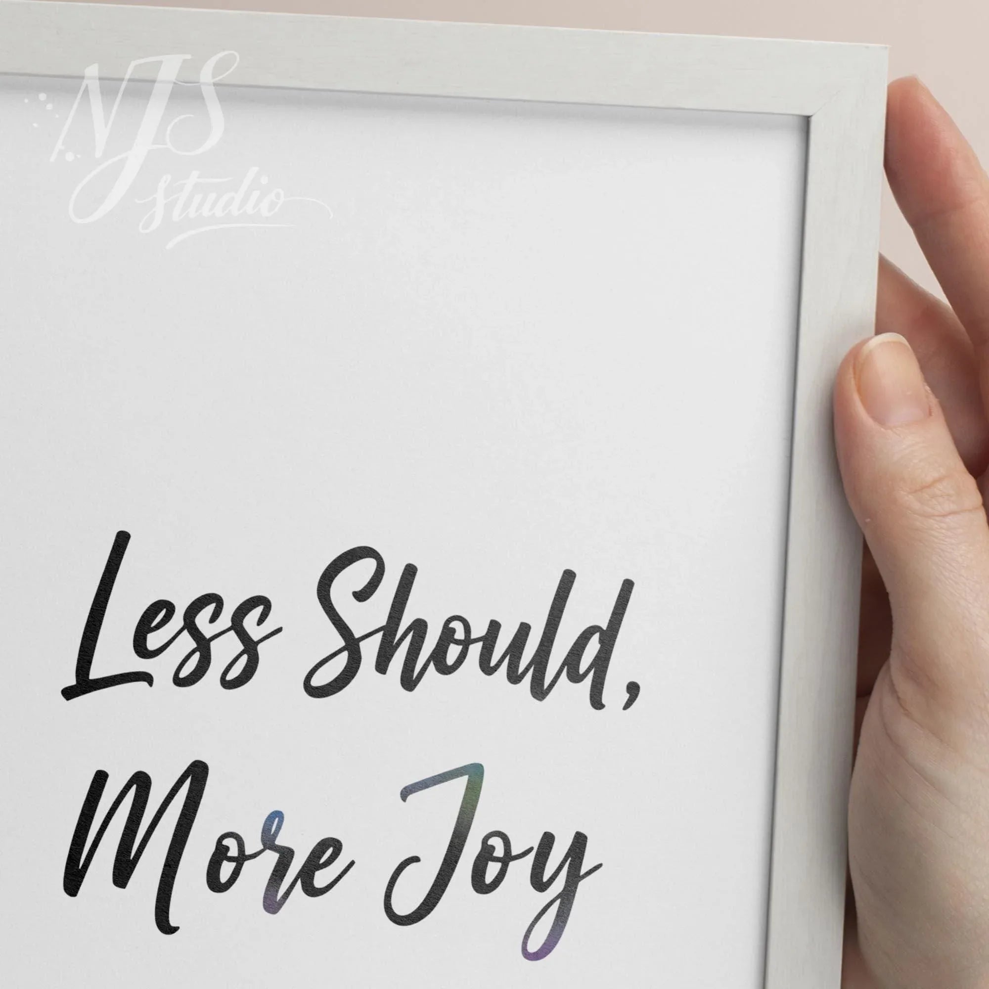 Close up of hand holding a white framed print, highlighting the colorful gradient texture on the word Joy.