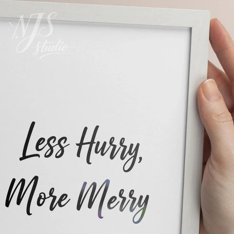 Close up of hand holding a white framed print showing the textured hand lettering detail of the word "Merry".