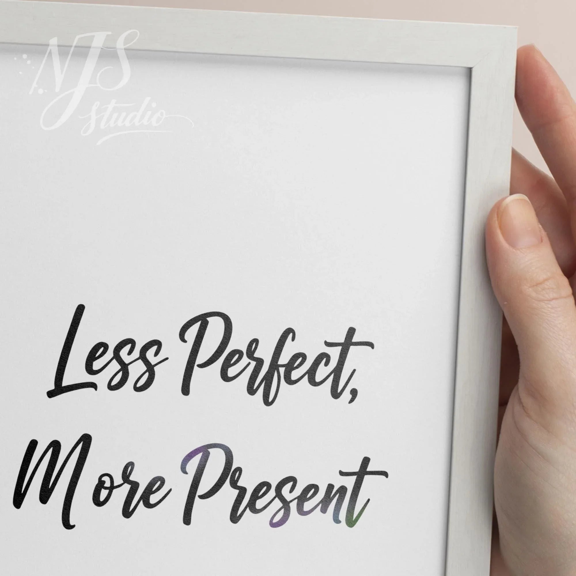 Close up of hand holding a white framed print showing the textured detail of the hand-lettered quote.