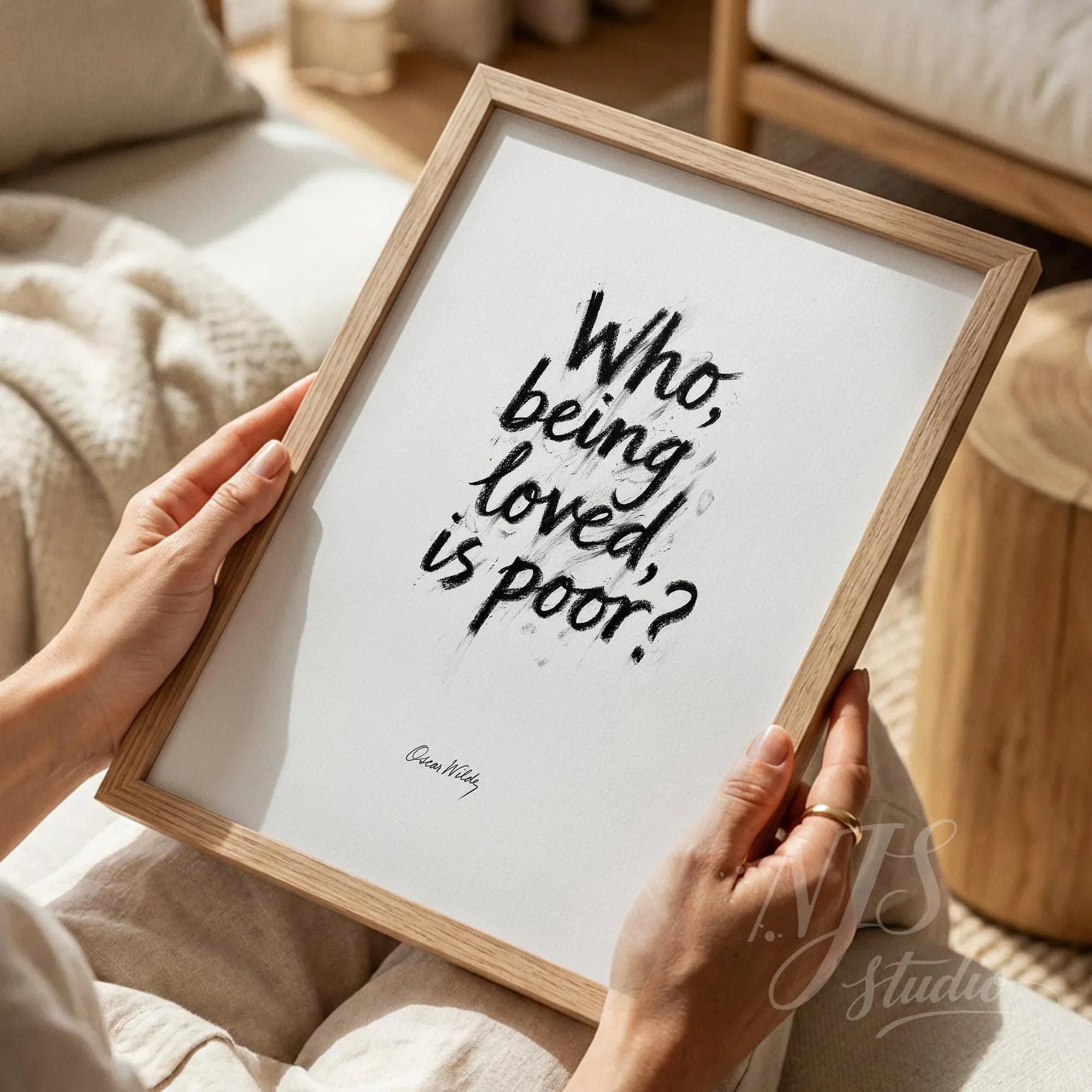 Close up of hands holding a wood framed print with artistic handwritten quote about love.