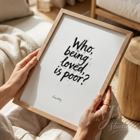 Close up of hands holding a wood framed print with artistic handwritten quote about love.