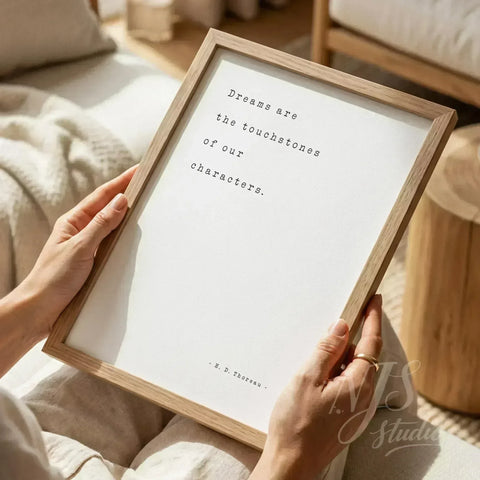 Close up of hands holding a wooden framed print with typewriter font quote about dreams.
