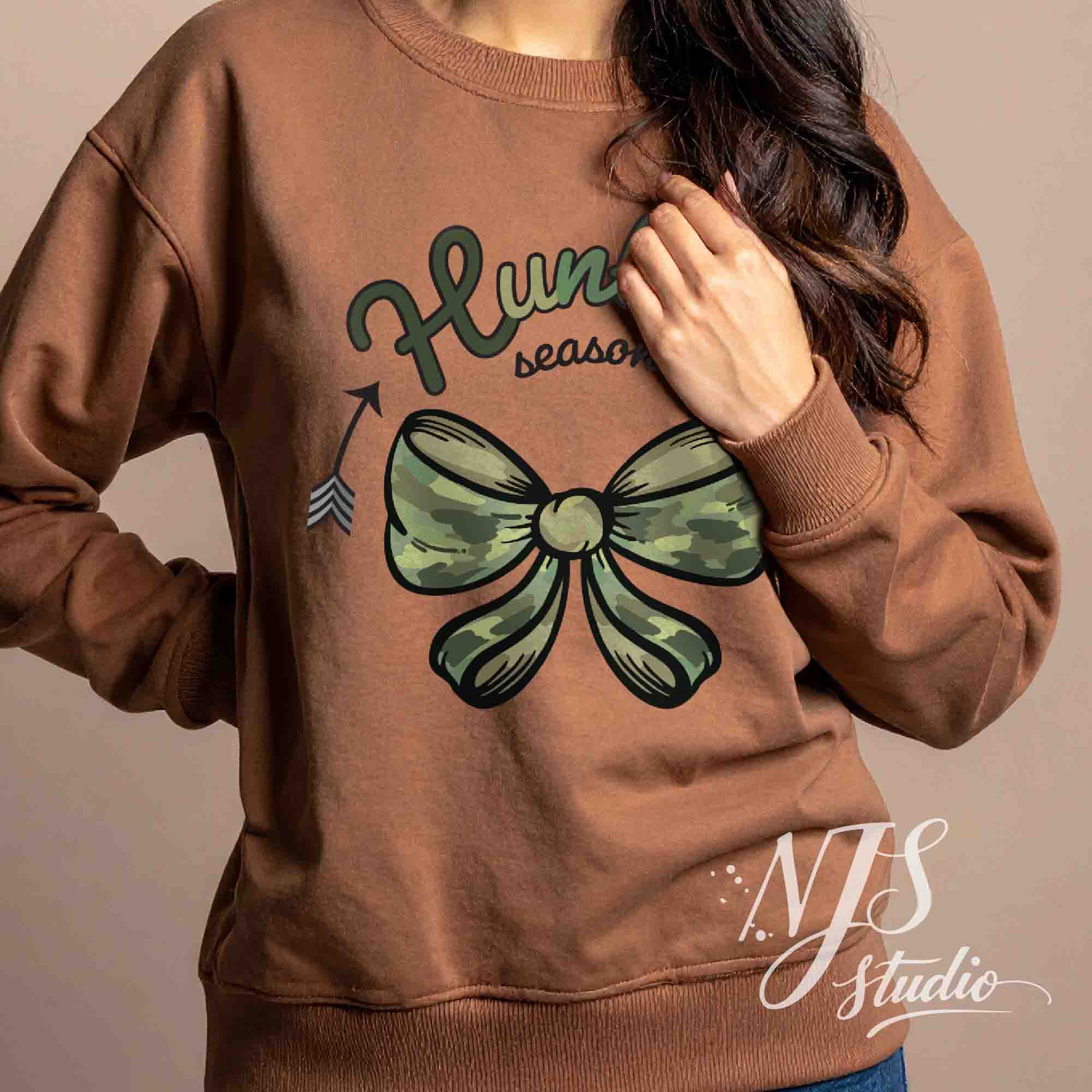 Brown sweatshirt with a green camo bow and hunting season graphic, modeled in a warm indoor setting.