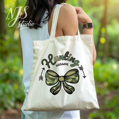 Canvas tote bag featuring a green camouflage bow and “Hunting Season” design, worn outdoors for a rustic fall lifestyle look.