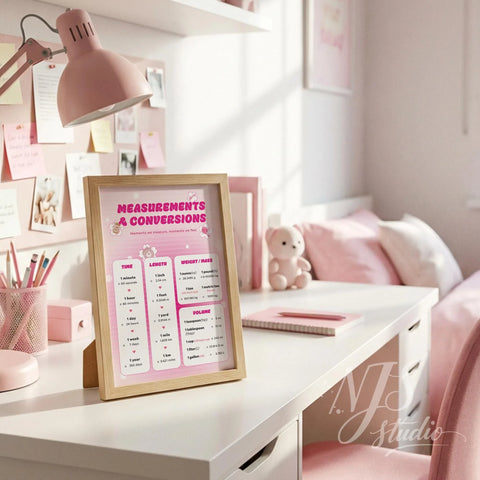 Wood framed pink math poster standing on a white study desk with pink accessories and a lamp.