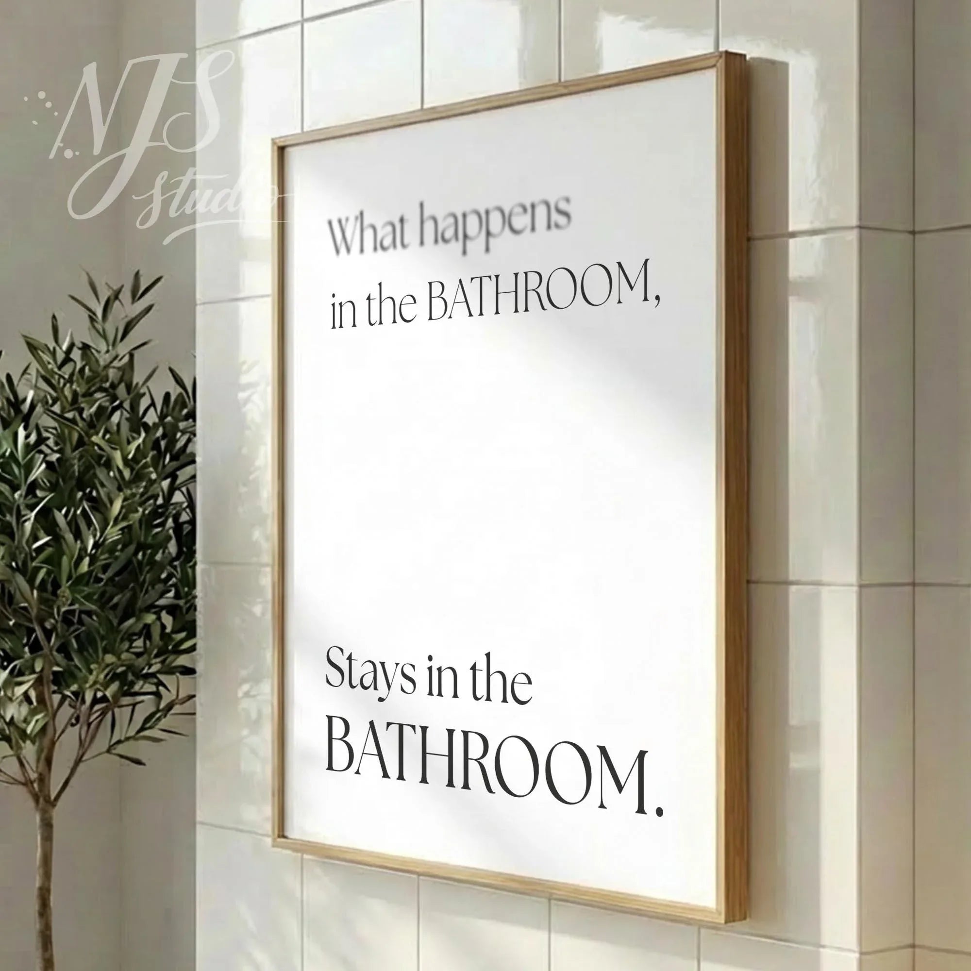 Modern bathroom poster featuring the phrase “What happens in the bathroom, stays in the bathroom,” styled in a vertical wood frame with soft daylight.