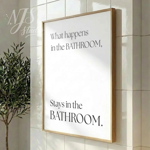 Modern bathroom poster featuring the phrase “What happens in the bathroom, stays in the bathroom,” styled in a vertical wood frame with soft daylight.