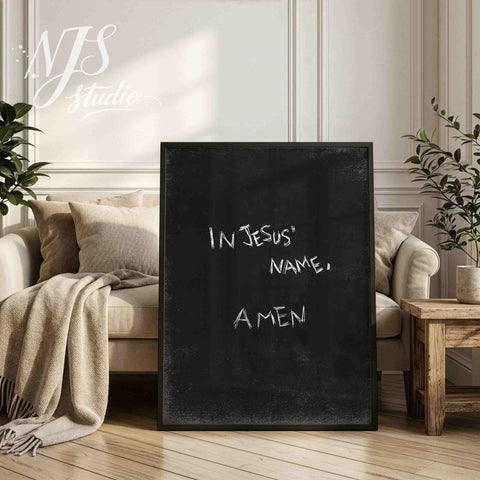 Black framed scriptural wall art standing on a light wooden chair near a window.