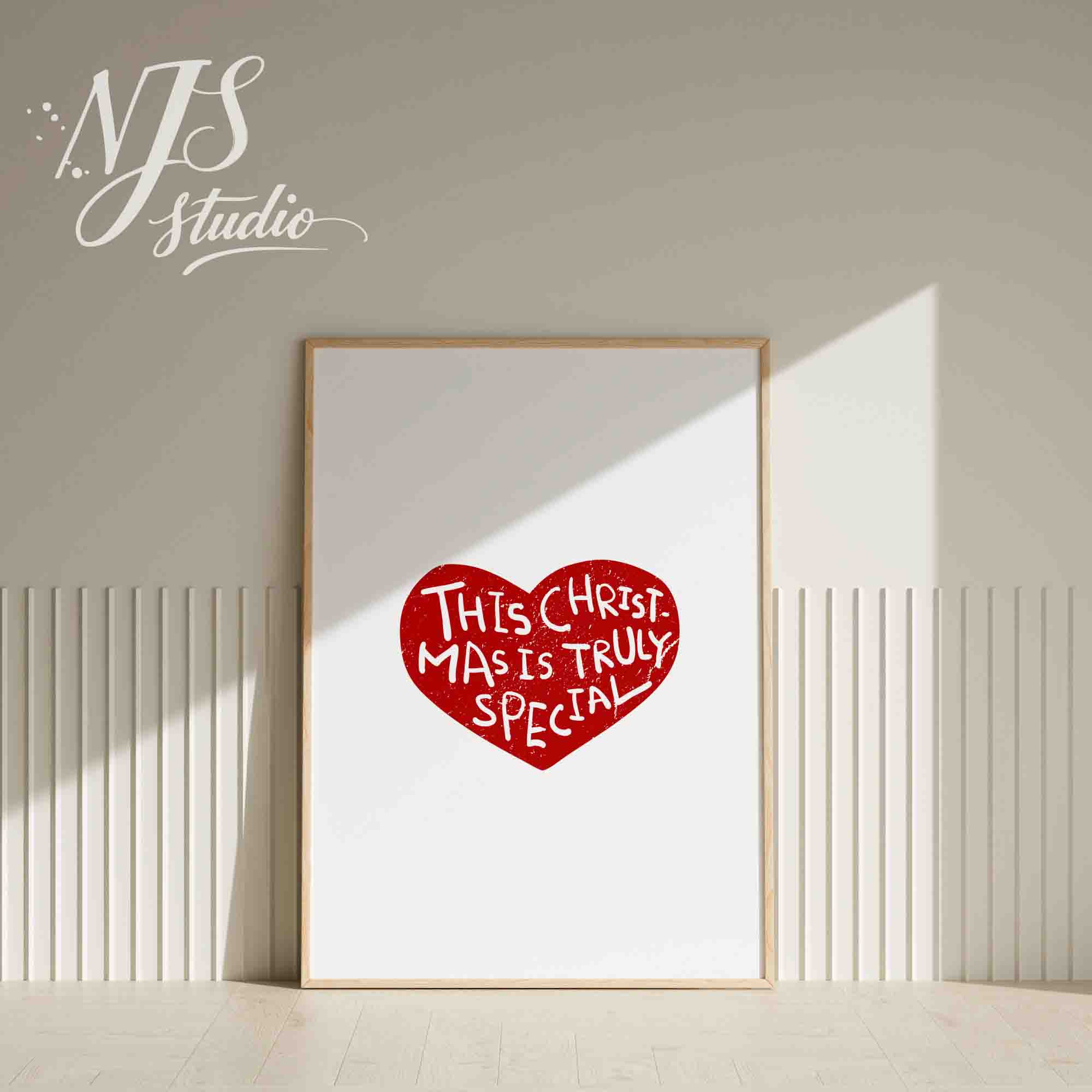 White framed simple Christmas wall art featuring a red heart design on a white shelf.