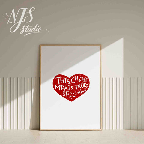 White framed simple Christmas wall art featuring a red heart design on a white shelf.