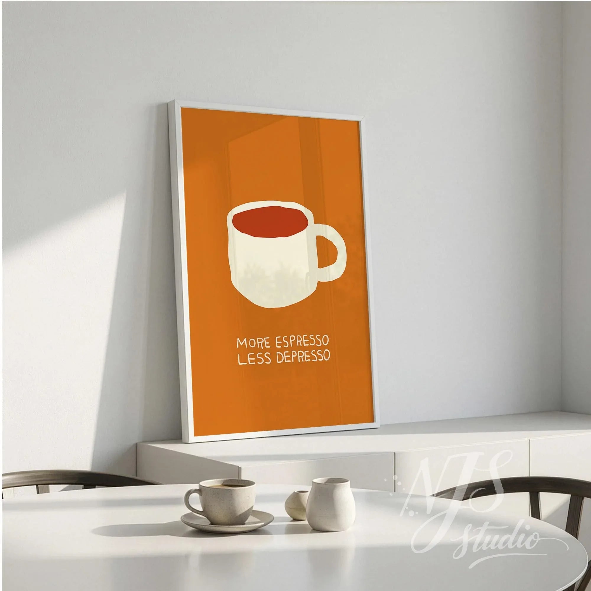 Framed cute coffee print standing on a white sideboard near a dining table with cups.