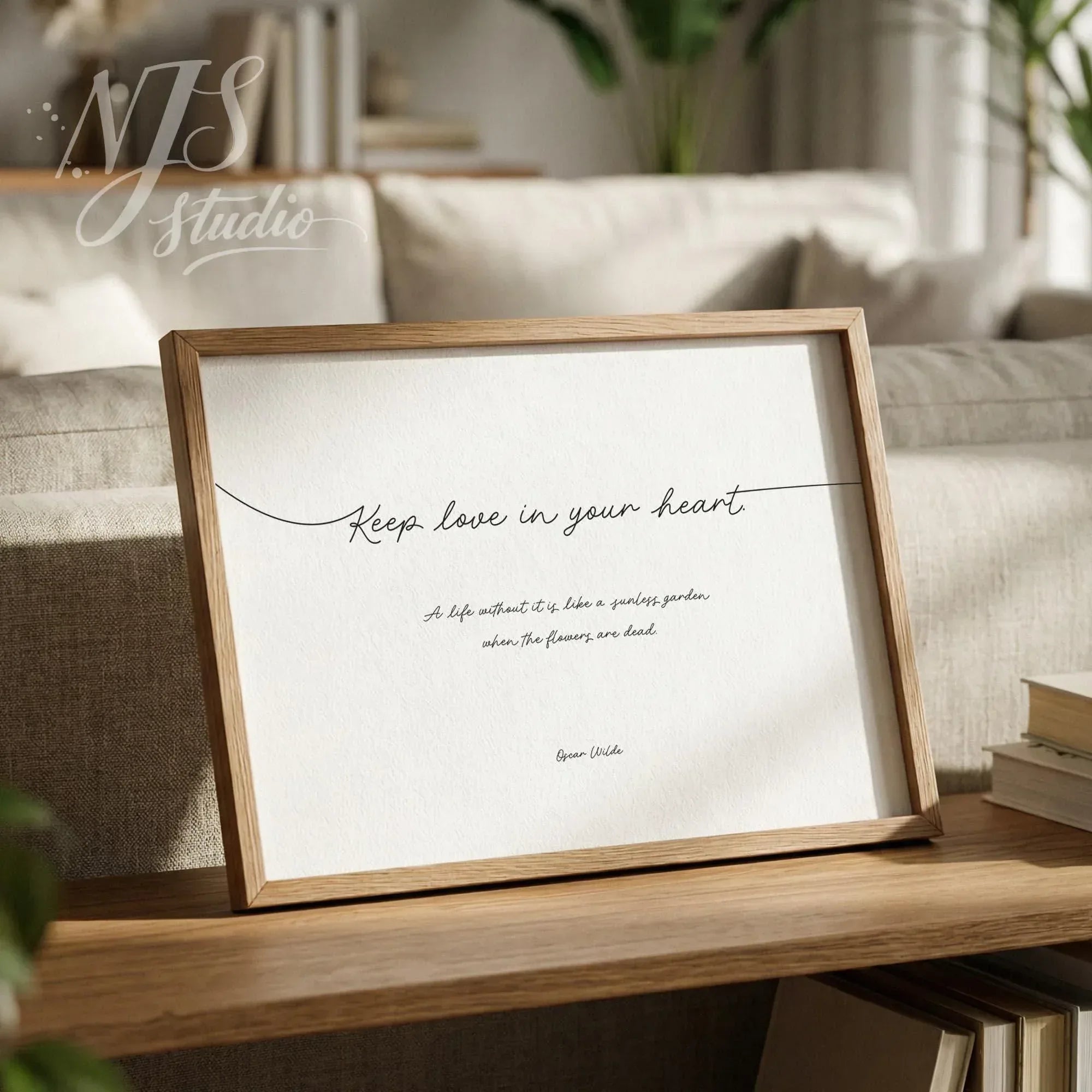 Wooden framed romantic quote art leaning on a shelf in a cozy modern living room with books.