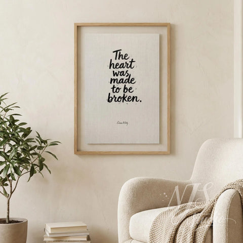 Framed brush lettering print hanging on a beige wall next to a cozy armchair in a reading nook.