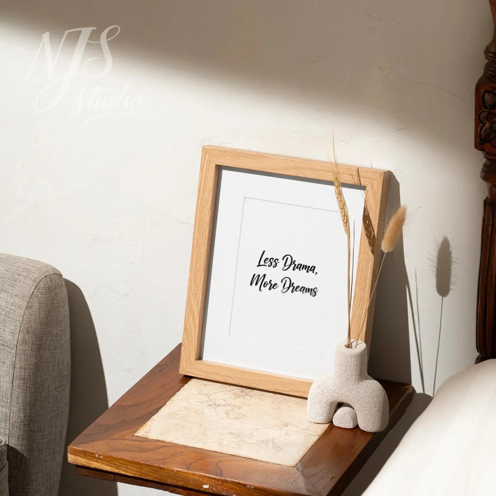 Small wood framed affirmation print on a bedside table with a modern vase, peaceful bedroom decor.