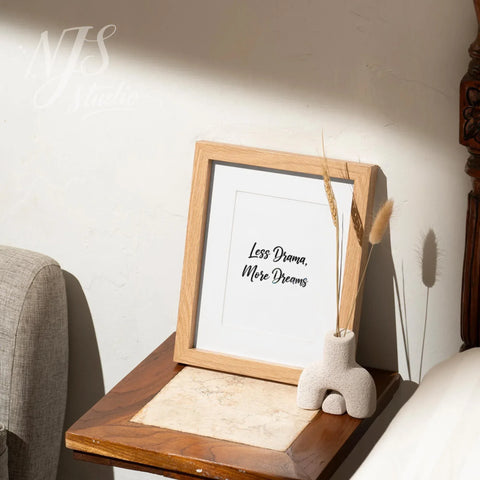 Small wood framed affirmation print on a bedside table with a modern vase, peaceful bedroom decor.