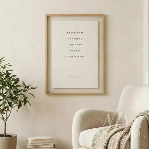 Large framed print on beige wall next to a comfortable armchair, reading Oscar Wilde's quote about mistakes.