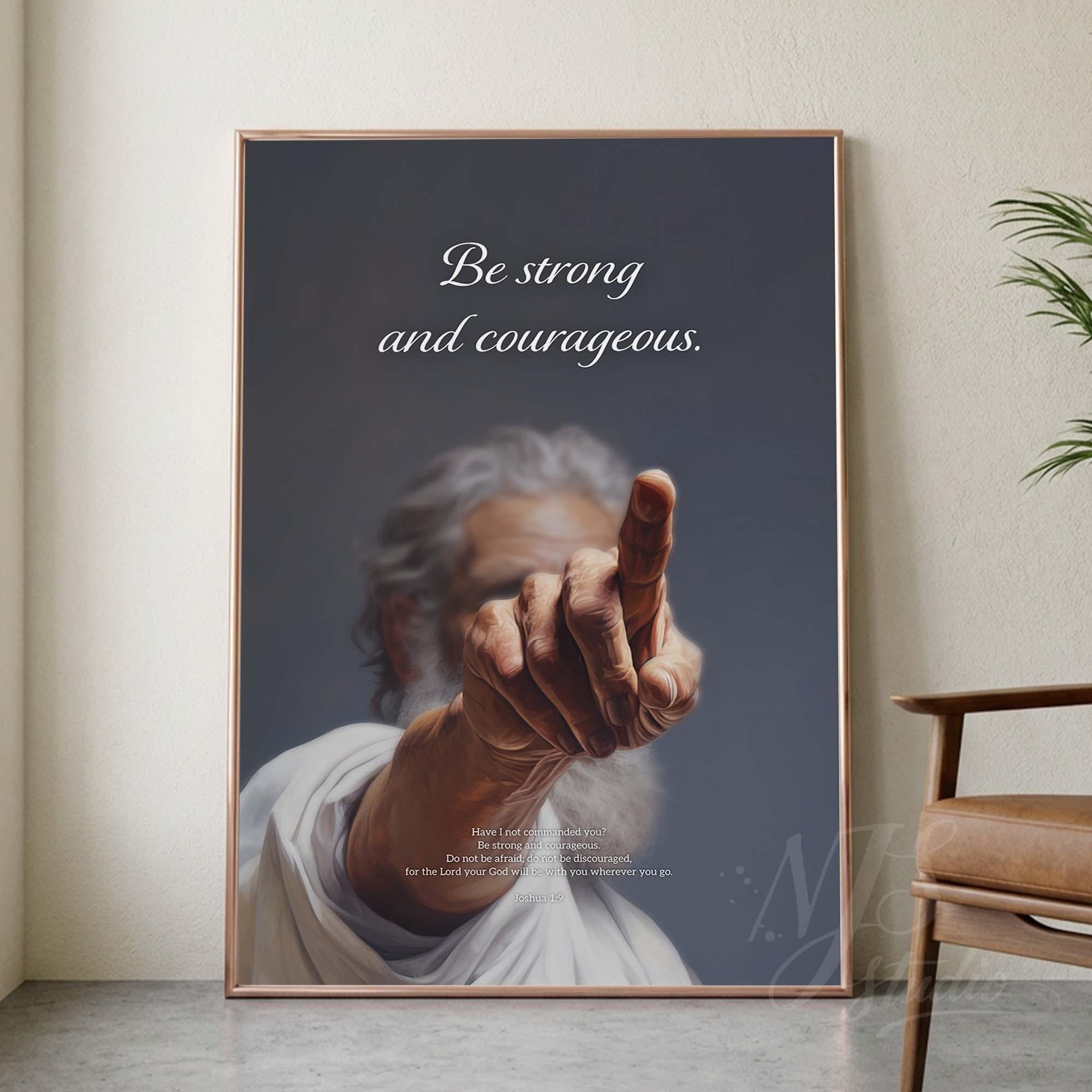 Framed poster with a hand reaching out and the text 'Be strong and courageous' in a room setting.