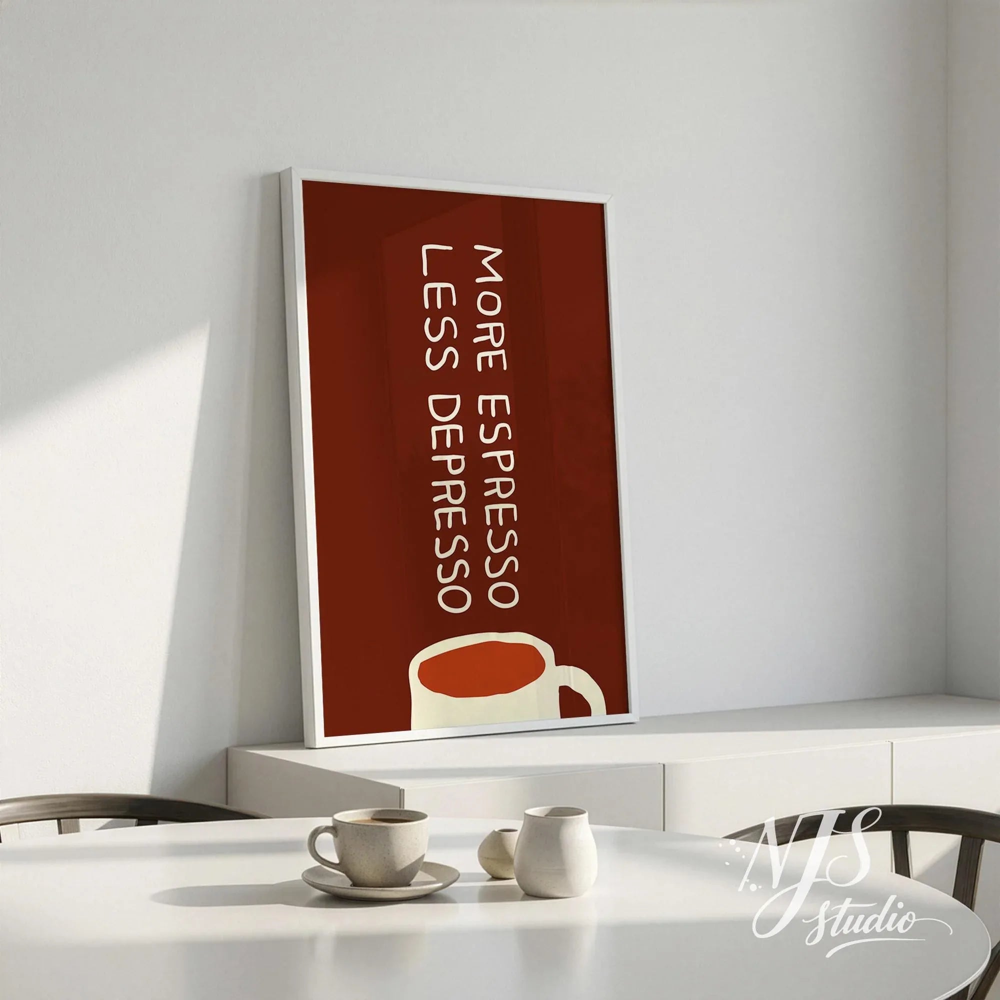 Framed deep brown coffee poster More Espresso Less Depresso leaning against a white wall on a modern sideboard.