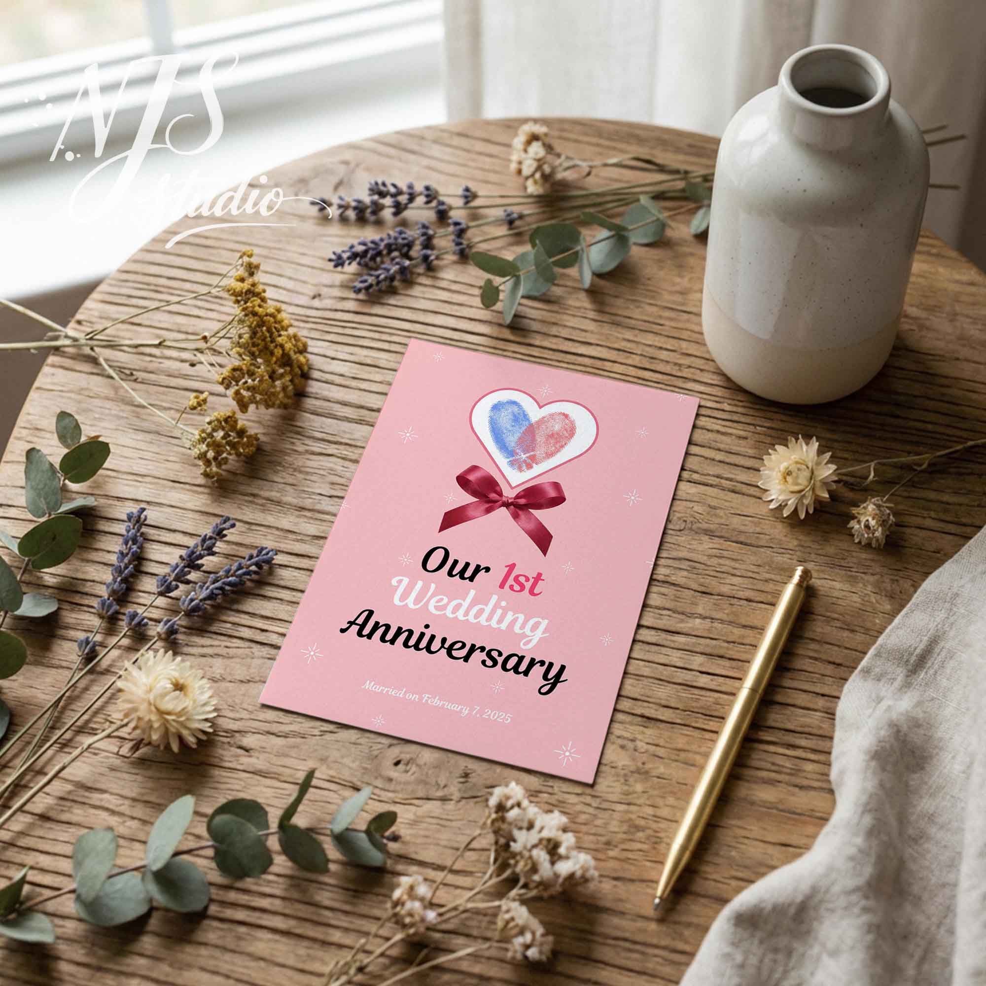 Wedding anniversary printable card with pink heart, ribbon, flowers, pen, and NJS studio logo.