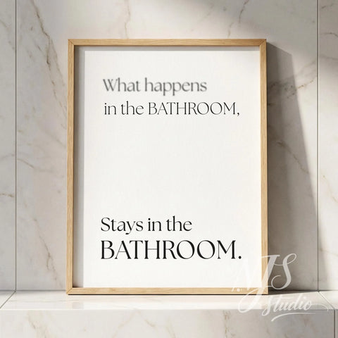 Minimal typography bathroom poster with the text “What happens in the bathroom, stays in the bathroom,” framed in natural wood against marble tiles.