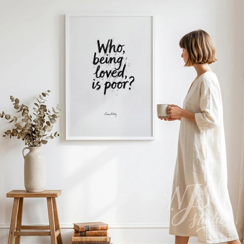Woman standing with coffee mug looking at a large framed brush lettering poster on a white wall.